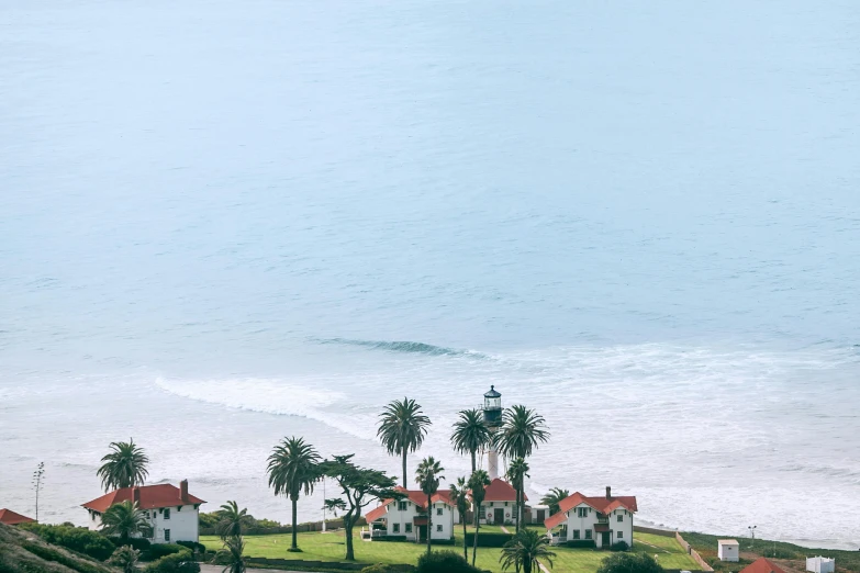 a couple of houses sitting on top of a lush green hillside, by Daren Bader, unsplash contest winner, surf, long beach background, vapor, hearst castle