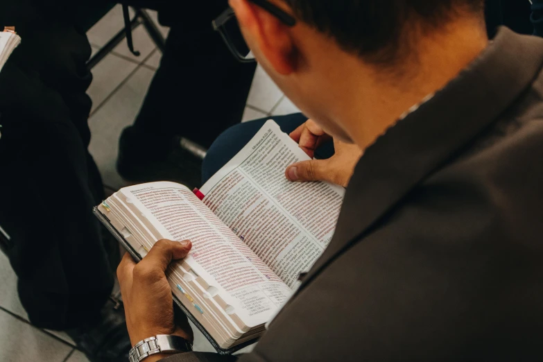 a man sitting in a chair reading a book, pexels, happening, religious, avatar image, closeup photograph, teaching