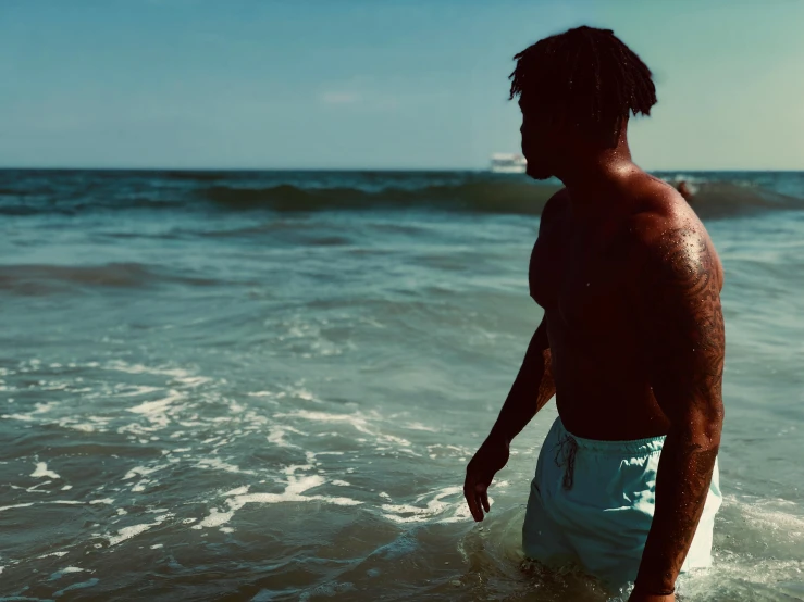 a man standing in the water at the beach, an album cover, by Quinton Hoover, pexels contest winner, playboi carti, rippling muscles, profile image, faded out colors