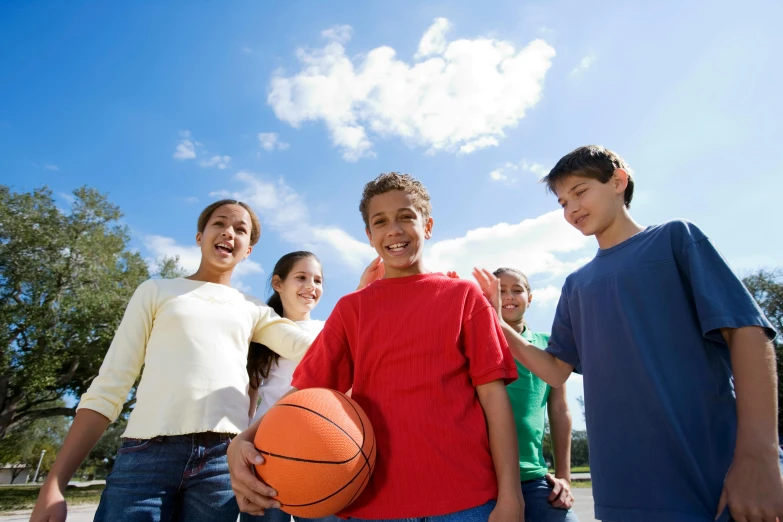 a group of children standing around a basketball ball, sunny environment, promotional image, thumbnail, various posed