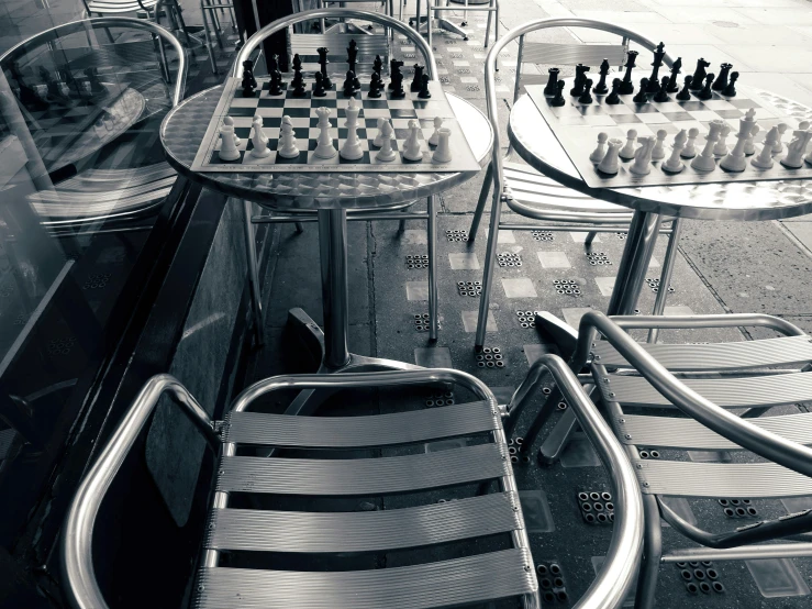 a black and white photo of a chess table and chairs, by Daniel Gelon, unsplash, un restaurant avec une terrasse, stainless steal, thumbnail, miscellaneous objects