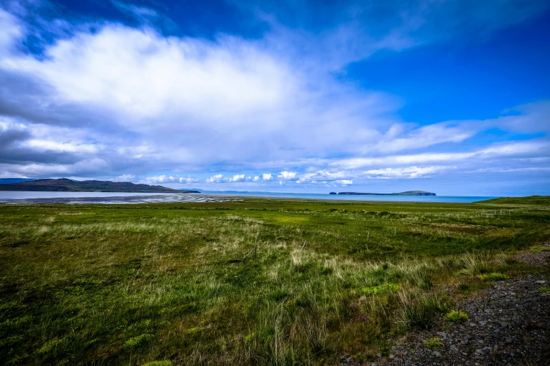 a grassy field with a body of water in the distance, unsplash, land art, islands on horizon, fan favorite, skye meaker, high resolution image