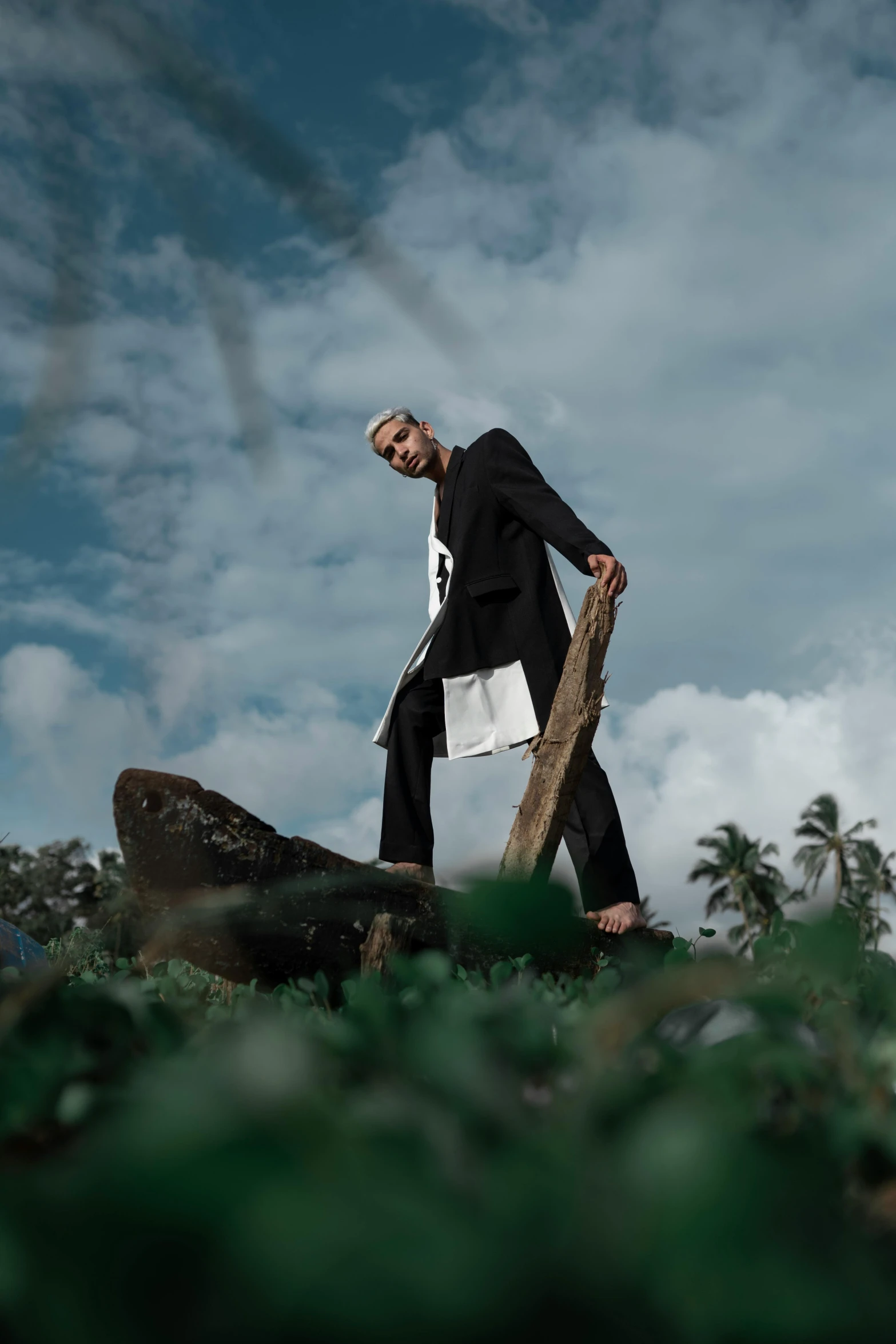 a man walking across a lush green field, an album cover, inspired by Byron Galvez, unsplash, surrealism, nun fashion model looking up, sri lanka, on stilts, beaches