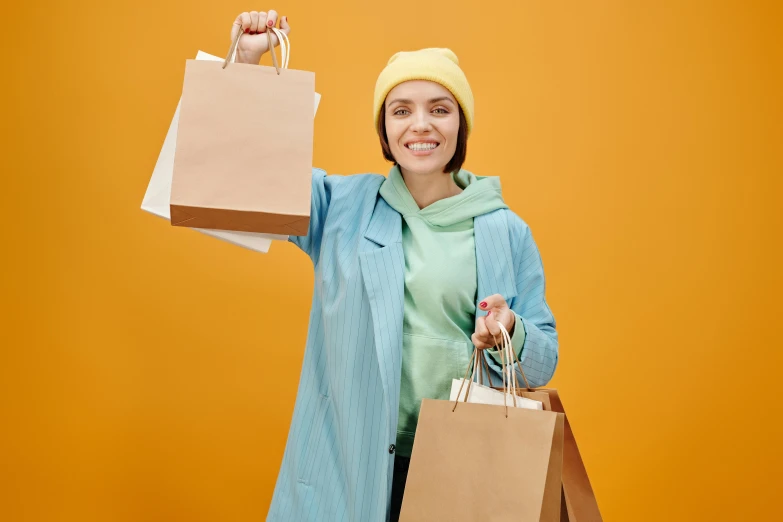 a woman in a blue coat holding shopping bags, pexels contest winner, yellow and olive color scheme, baggy clothing and hat, happy appearance, 🦩🪐🐞👩🏻🦳