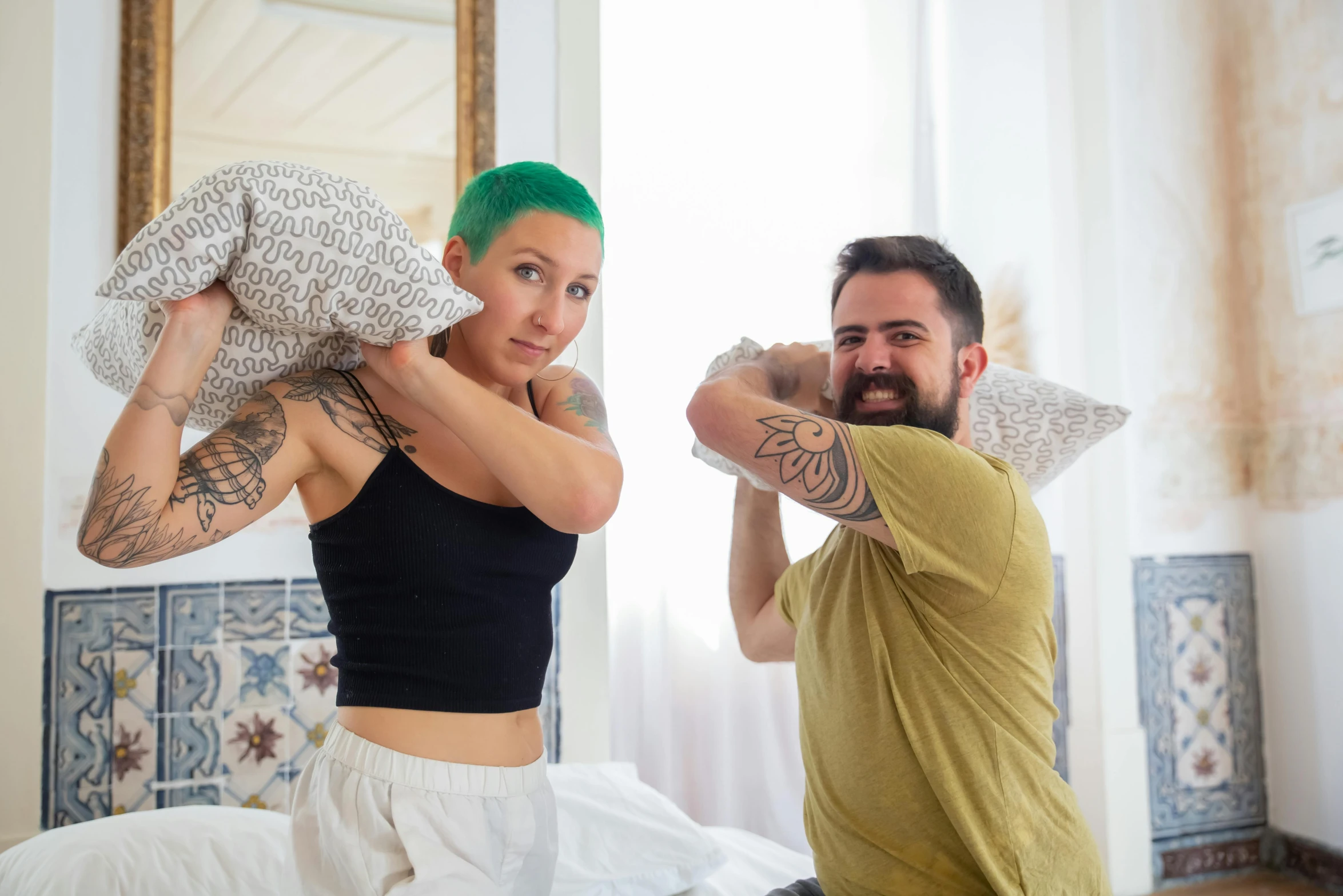 a man standing next to a woman on top of a bed, a photo, pexels contest winner, antipodeans, short green hair, punching in a bag, with tattoos, pillows