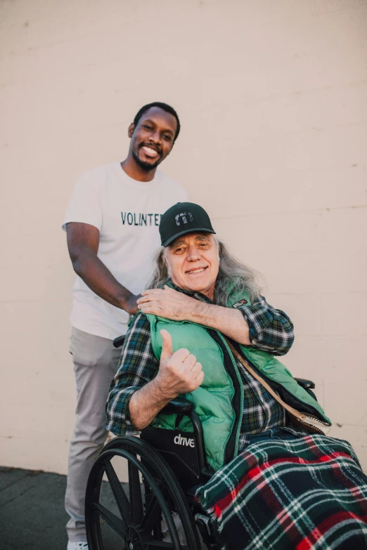 a man standing next to a woman in a wheelchair, a black and white photo, by Gavin Hamilton, portrait of billie eilish, a black man with long curly hair, portrait of don knotts, happy friend