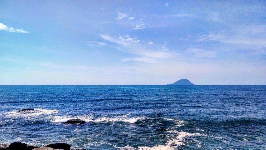 a large body of water with a small island in the distance, a picture, unsplash, mingei, azure blue sky, photo on iphone, vulcano, conde nast traveler photo