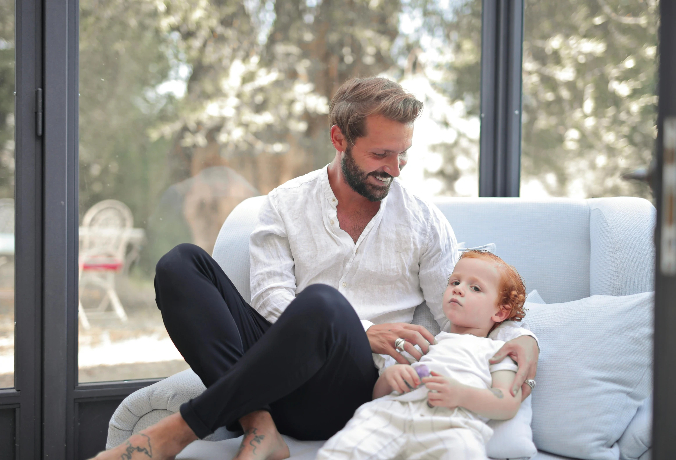 a man sitting on a couch holding a baby, pexels contest winner, renaissance, gregoire and manon, 4yr old, bearded, wearing white pajamas