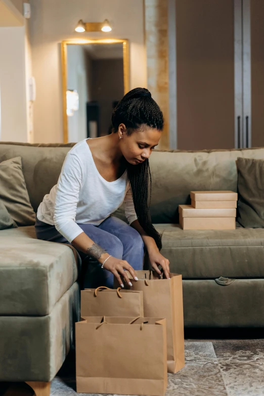 a woman sitting on a couch in a living room, packaging, shopping groceries, ashteroth, bending down slightly