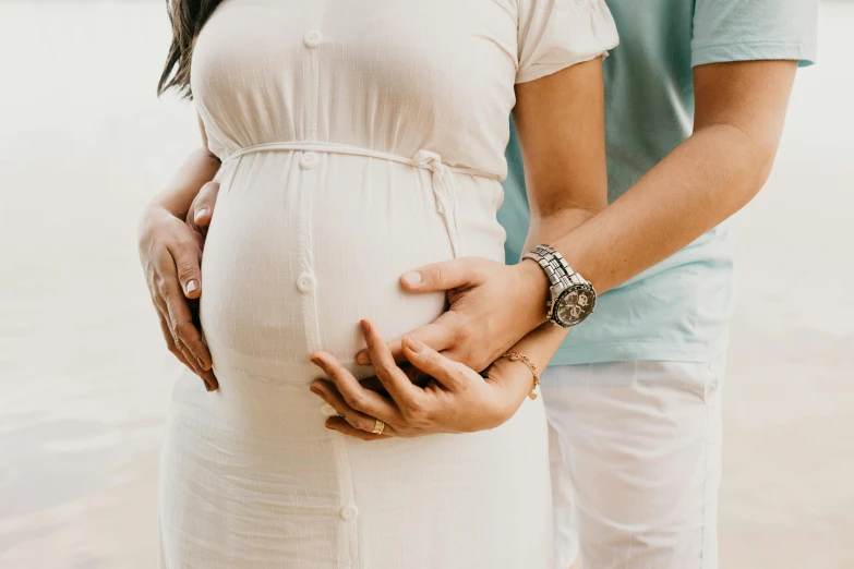 a pregnant woman standing next to a man on a beach, pexels contest winner, symbolism, closeup of arms, wearing a white hospital gown, transparent background, 1 4 9 3