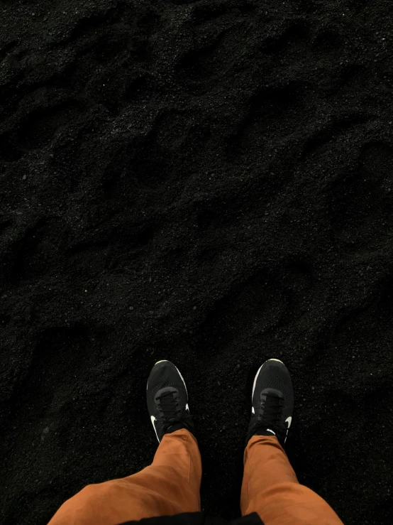 a person standing on top of a black sand beach, sneakers, areas rugs, pitch black, ( ( dark skin ) )