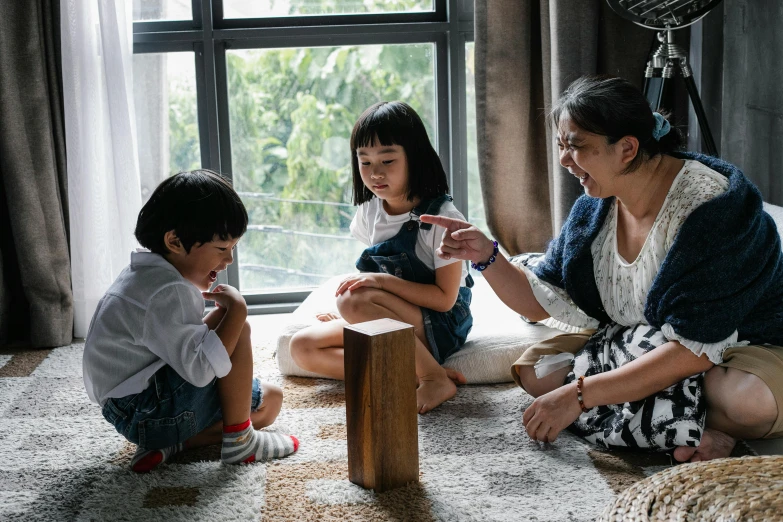 a woman and two children sitting on the floor, inspired by Ni Duan, pexels contest winner, tabletop game board, looking around a corner, rectangle, profile image