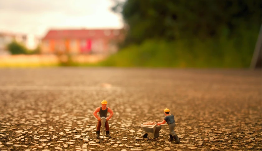 a couple of figurines sitting on top of a road, pexels contest winner, people at work, toy photo, grain”, micro detail