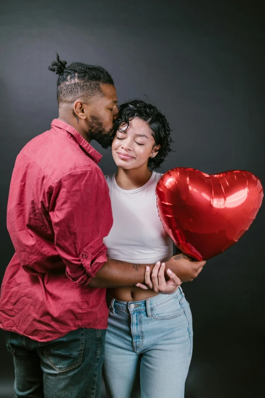 a man standing next to a woman holding a heart shaped balloon, by Cosmo Alexander, pexels, renaissance, african american, studio photoshoot, hugging each other, crimson themed