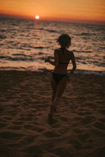 a woman running on the beach at sunset, an album cover, pexels contest winner, black bikini, sydney sweeney, grainy photo, profile image