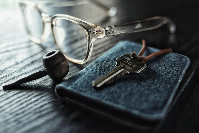 a pair of glasses sitting on top of a book next to a pipe, a still life, unsplash, modernism, metal key for the doors, pair of keys, square rimmed glasses, detailed shot