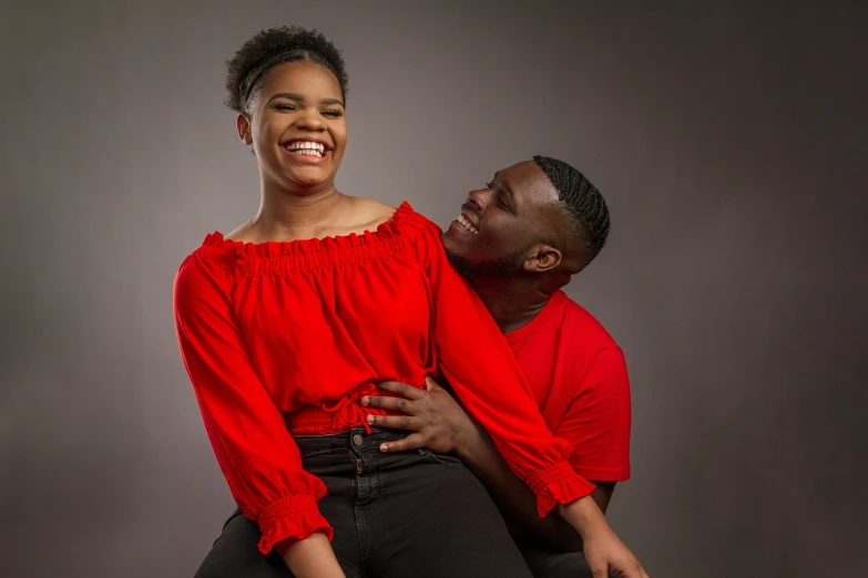 a man and a woman sitting next to each other, an album cover, by Ingrida Kadaka, pexels, wearing red clothes, head bent back in laughter, godwin akpan, photoshoot poses