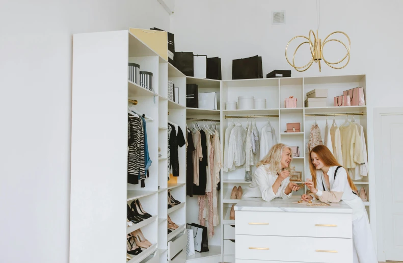 a couple of women standing next to each other in a closet, by Nicolette Macnamara, pexels contest winner, luxury furniture, on a white table, people at work, scandinavian style