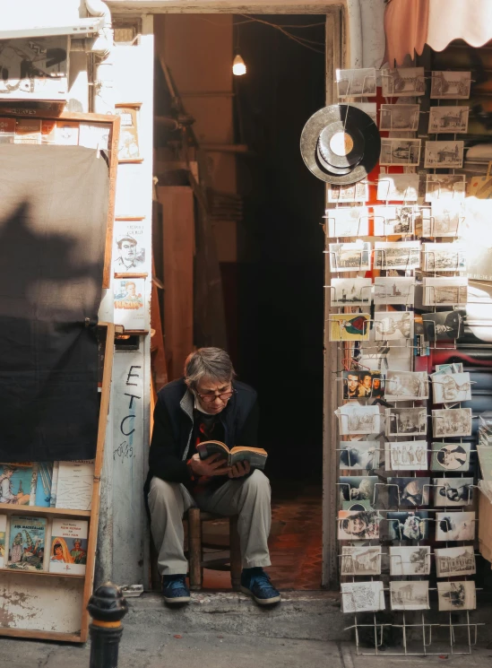 a man sitting on a chair in front of a book store, pexels contest winner, art & language, in an alley, an oldman, profile image, gallery display photograph