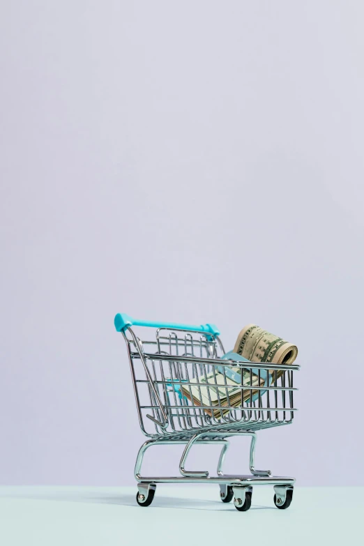 a shopping cart filled with money sitting on top of a table, pexels, minimalism, square, b - roll, mint, low fi