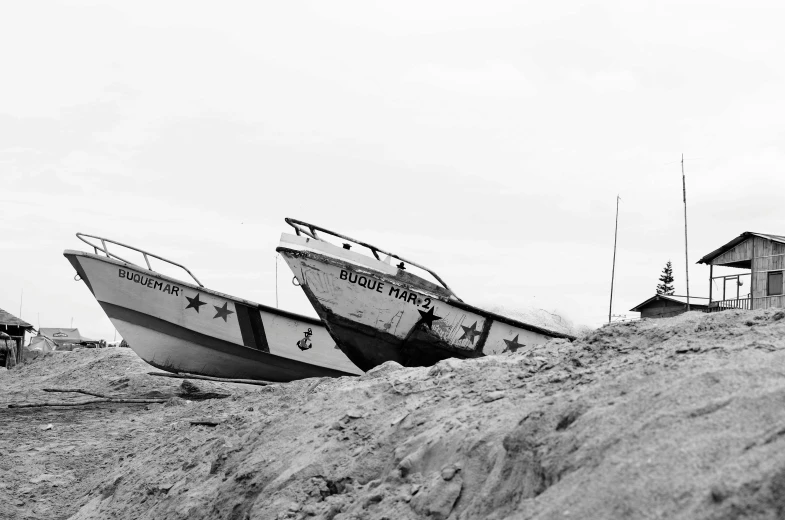 a couple of boats that are sitting in the sand, a black and white photo, by Matija Jama, auto-destructive art, black stars, photographic print, low quality photo, 🪔 🎨;🌞🌄