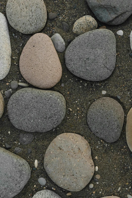 a group of rocks sitting on top of a sandy beach, an album cover, by Ben Zoeller, land art, cobblestone street, detail texture, ((rocks)), small