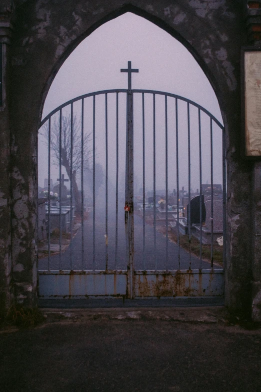 a gate that has a cross on it, an album cover, gloomy/wet atmosphere, low quality photo, cementary, ghetto