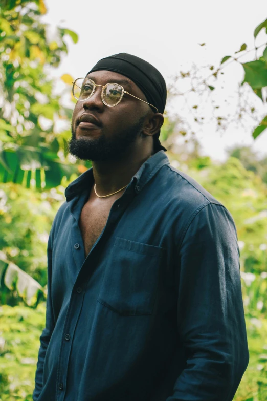 a man standing in the middle of a forest, an album cover, by Theodore Major, trending on pexels, thick glasses, ( ( dark skin ) ), gardens, saintly