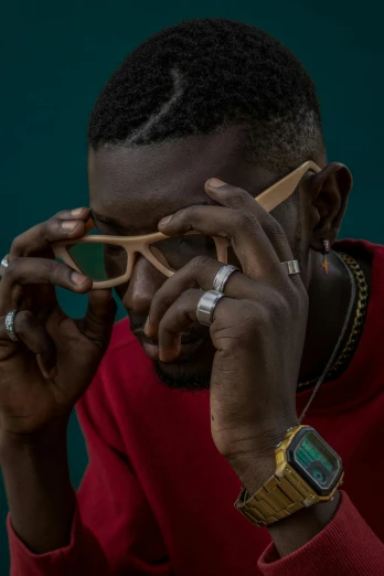 a man in a red shirt talking on a cell phone, an album cover, inspired by David Bailly, trending on unsplash, afrofuturism, square rimmed glasses, wooden jewerly, yasuke 5 0 0 px models, shot with sony alpha 1 camera
