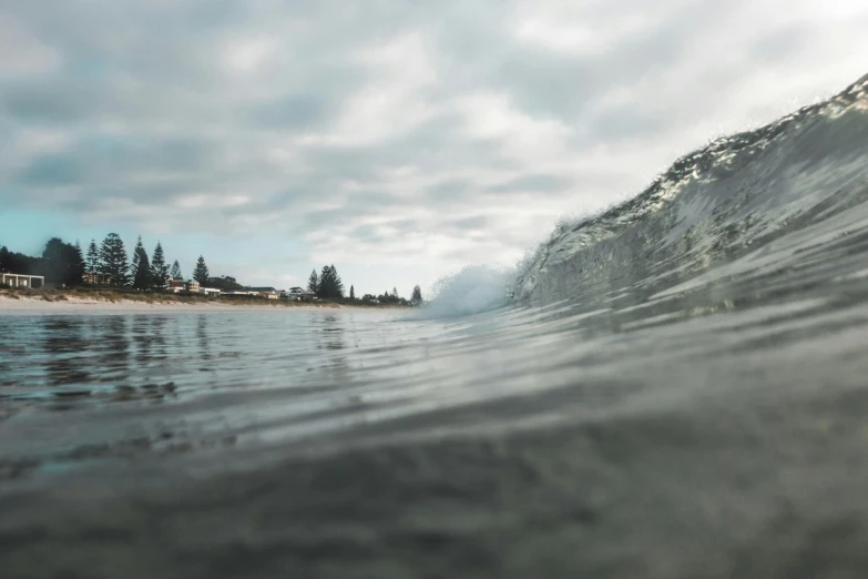 a man riding a wave on top of a surfboard, by Peter Churcher, unsplash contest winner, photorealism, manly, view from the ground, big overcast, waterline refractions
