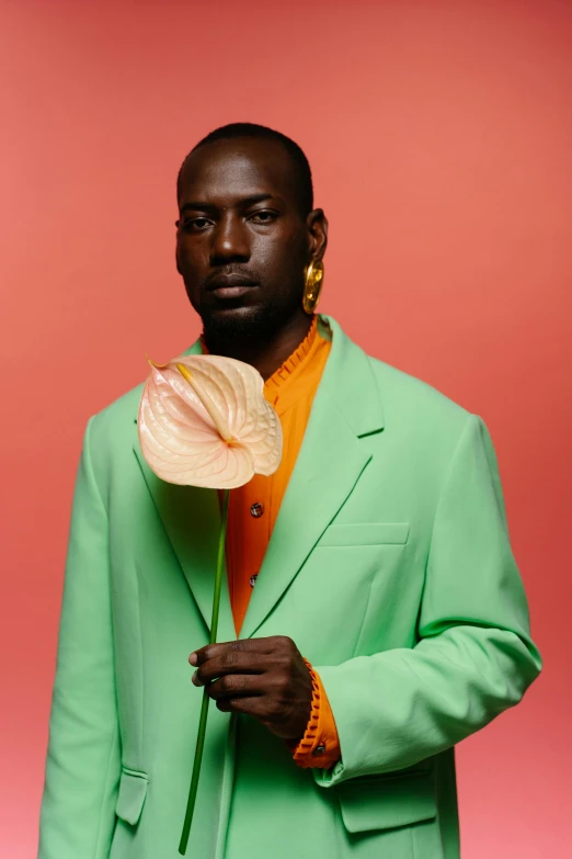 a man in a green suit holding a flower, an album cover, by Winona Nelson, trending on pexels, neo-dada, adut akech, color studio portrait, ( ( ( colorful ) ) ), pastel'