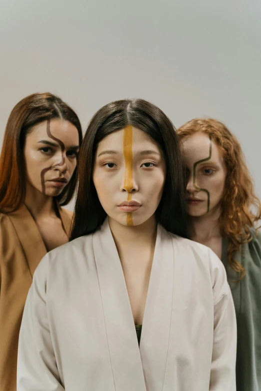 a group of women standing next to each other, an album cover, inspired by Kim Tschang Yeul, trending on pexels, renaissance, facepaint, earth tones, neanderthal people, asian man