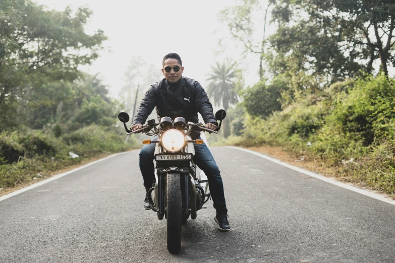 a man riding on the back of a motorcycle down a road, a portrait, pexels contest winner, assamese aesthetic, in front of a forest background, wearing oakley sunglasses, thumbnail