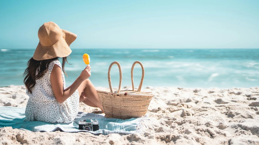 a woman sitting on the beach eating an ice cream, pexels contest winner, yellow parasol, skincare, candy treatments, straw hat