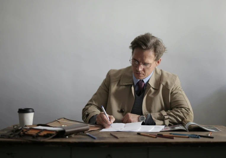 a man sitting at a table writing on a piece of paper, professor clothes, ignant, thumbnail, brown