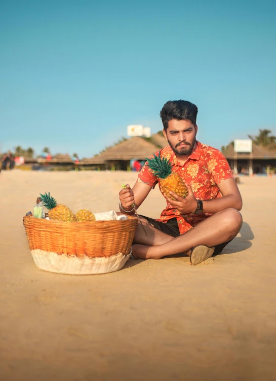 a man sitting on the beach with a basket of pineapples, pexels contest winner, vijay jayant props, avatar image, model pose, drink
