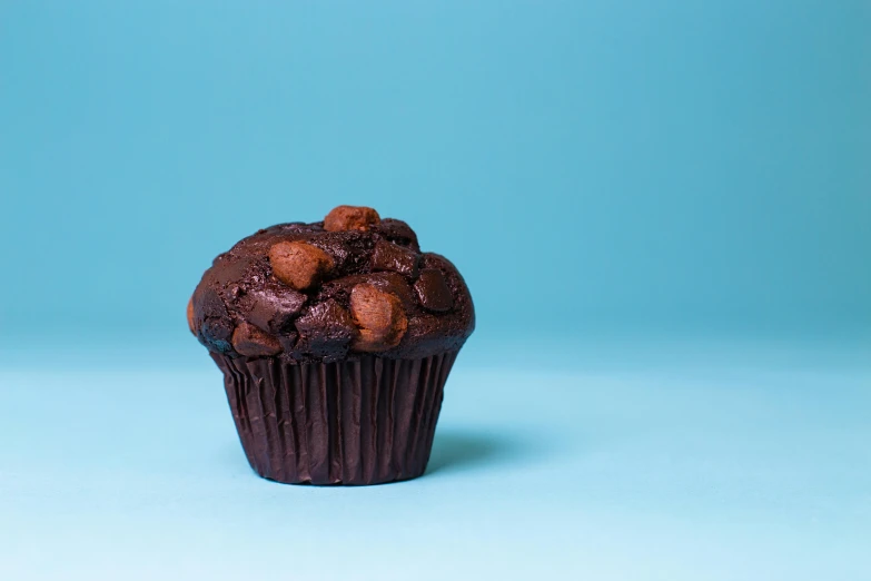 a chocolate muffin sitting on top of a blue surface, unsplash, hyperrealism, medium format, sweets, 15081959 21121991 01012000 4k, thumbnail