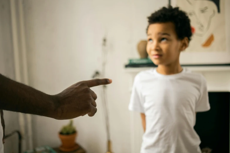 a little boy standing next to a man in a living room, pexels contest winner, pointing index finger, black, bullying, gif