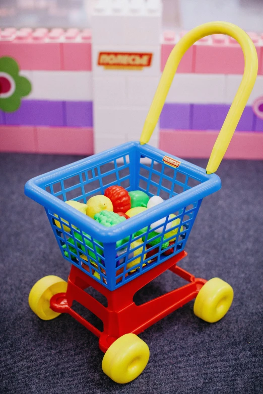 a toy shopping cart with balls in it, a picture, square, multi - coloured, brick, indoor picture