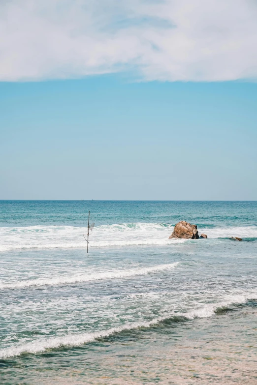 a man standing on top of a sandy beach next to the ocean, floating rocks, sri lankan landscape, people angling at the edge, 2019 trending photo