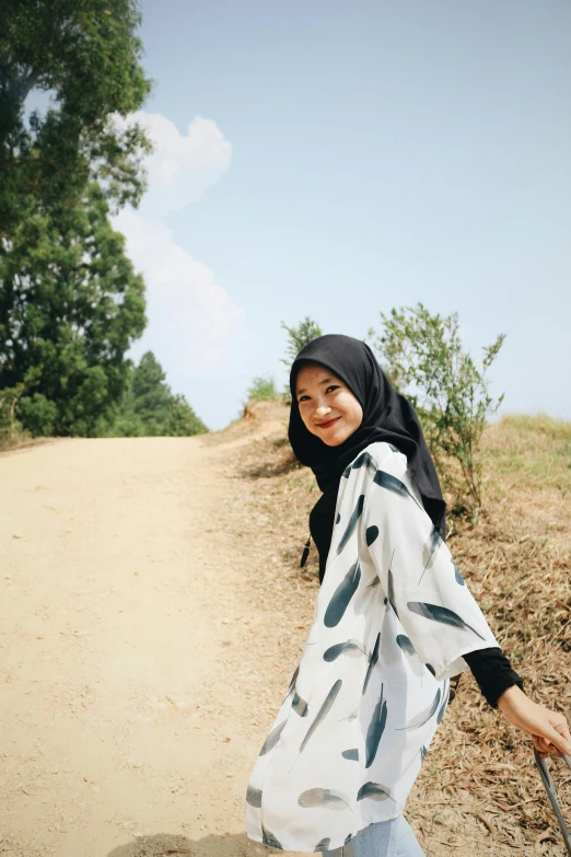 a woman walking down a dirt road with a suitcase, inspired by Nazmi Ziya Güran, hurufiyya, happily smiling at the camera, malaysian, patterned, white sleeves