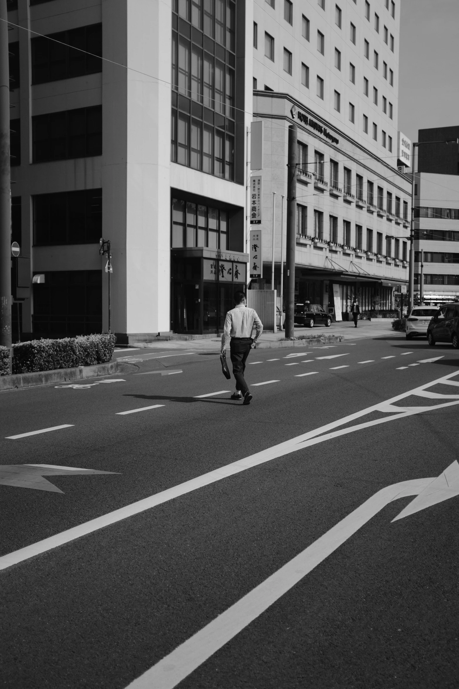 a man riding a skateboard down a street next to tall buildings, a black and white photo, by Tadashige Ono, unsplash, postminimalism, tsutomu kitazawa, square lines, intersection, people walking around