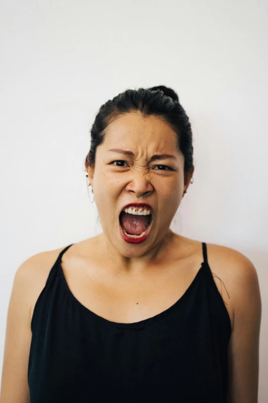 a woman making a face with her mouth wide open, inspired by Kanō Tan'yū, pexels contest winner, renaissance, angry light, south east asian with round face, plain background, mixed race woman