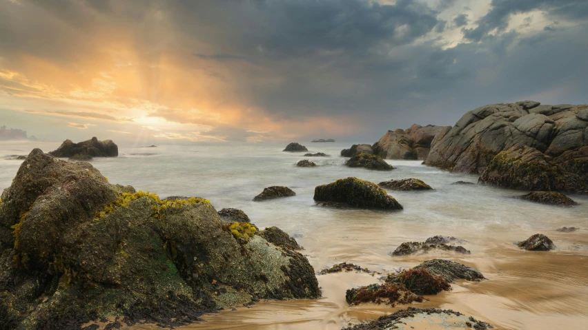 a group of rocks sitting on top of a sandy beach, unsplash contest winner, romanticism, sunset panorama, stormy overcast, steven outram hd, large scale photo