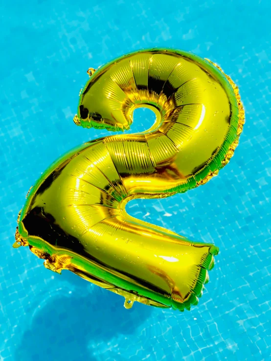 a number 2 balloon floating in a pool, by Julia Pishtar, shutterstock contest winner, happening, lime and gold hue, 🍸🍋, gold foil, two arms