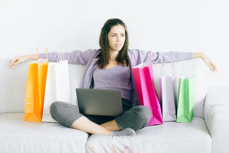 a woman sitting on a couch with shopping bags, trending on pixabay, sitting in an empty white room, sitting in front of computer, promo image, coloured photo