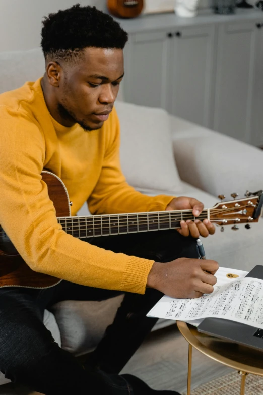 a man sitting on a couch playing a guitar, by Daniel Seghers, pexels contest winner, emmanuel shiru, signing a bill, he is wearing a brown sweater, promotional image