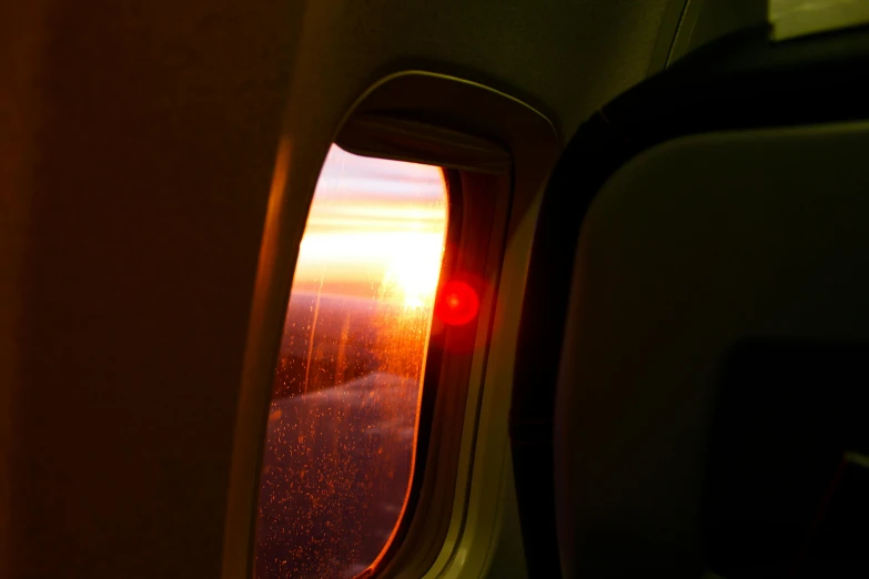 the sun is setting through the window of an airplane, by Jessie Algie, pexels contest winner, romanticism, red and yellow light, cabin lights, lit from the side, detailed light