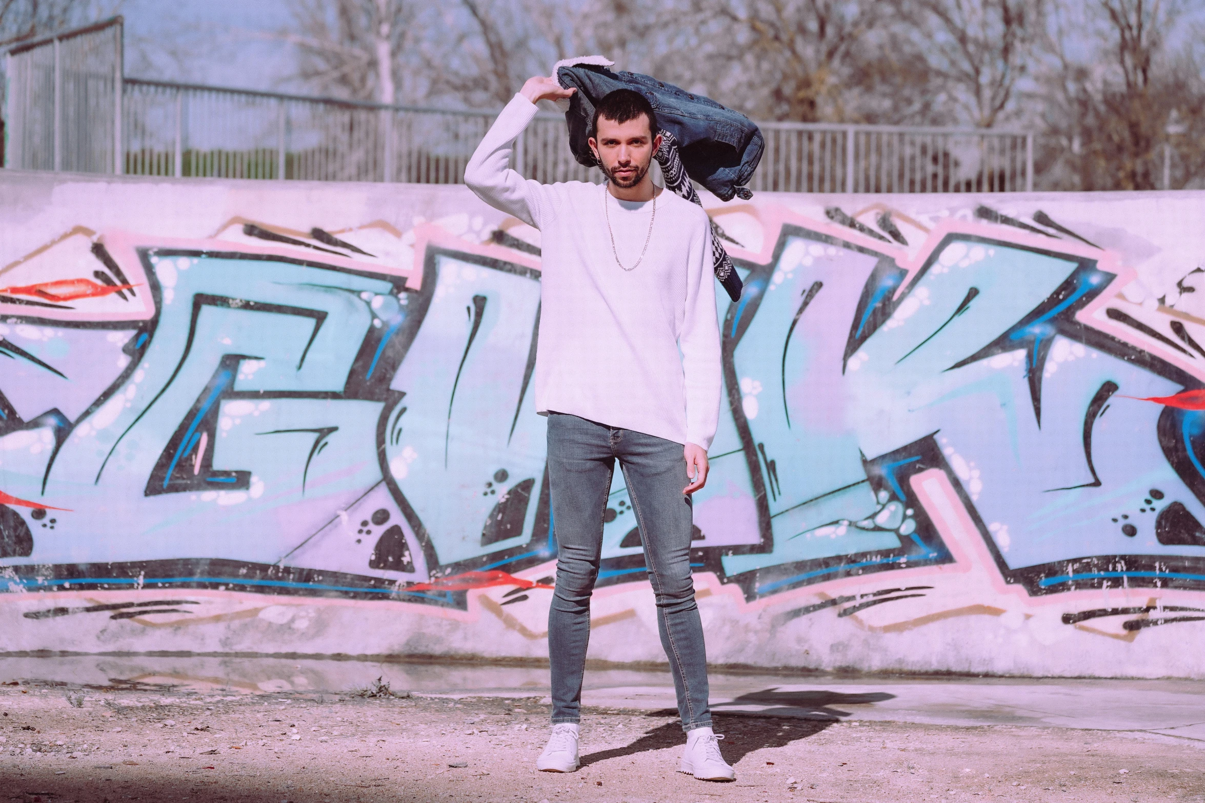 a man standing in front of a graffiti covered wall, an album cover, pexels contest winner, wearing a white sweater, lucas graziano, pointè pose, avatar image