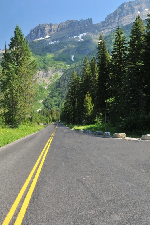 a man riding a skateboard down the middle of a road, glacier national park, streetview, national geograph, avatar image